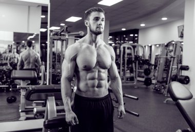 Very power athletic guy bodybuilder. Posing in front of a mirror