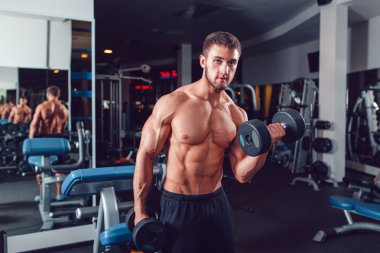 Çok güç atletik adam vücut geliştirmeci, egzersiz dumbbells ile yürütmek