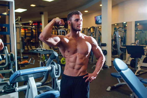 Very power athletic guy bodybuilder. Posing in front of a mirror — Stockfoto