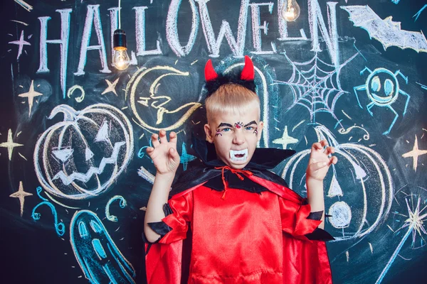 Menino em um traje de Drácula posando no fundo da inscrição Halloween — Fotografia de Stock