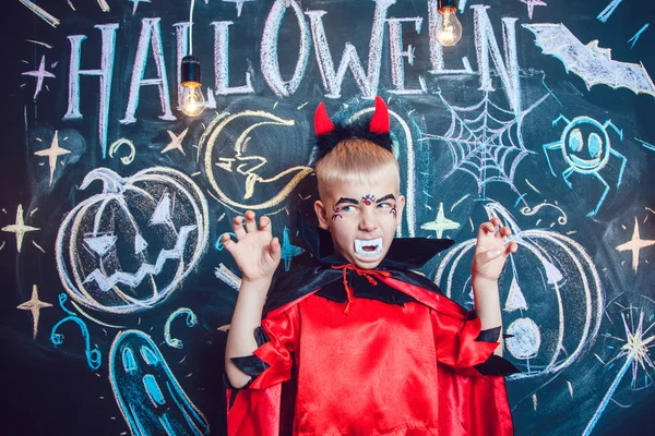 Menino em um traje de Drácula posando no fundo da inscrição Halloween — Fotografia de Stock