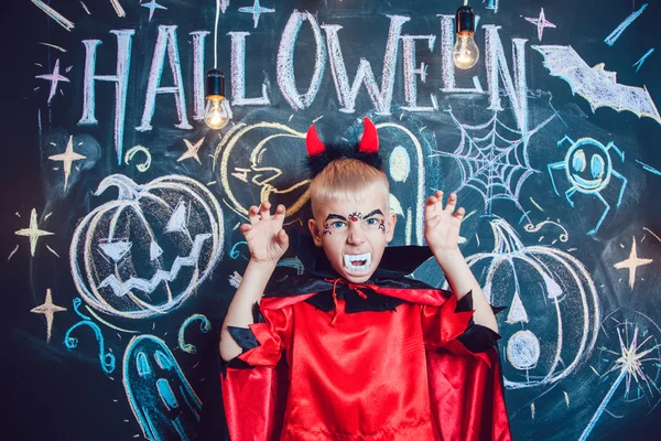 Boy in a Dracula kostum berpose di latar belakang tulisan Halloween — Stok Foto