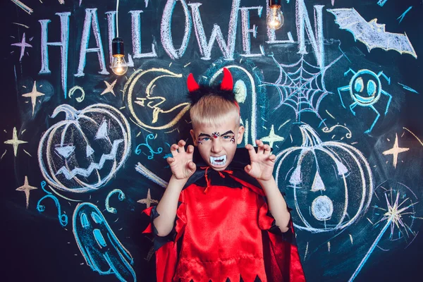 Menino em um traje de Drácula posando no fundo da inscrição Halloween — Fotografia de Stock