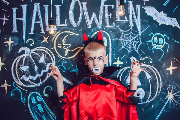 Menino em um traje de Drácula posando no fundo da inscrição Halloween — Fotografia de Stock