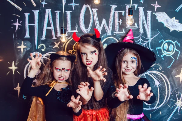 Girls, berpakaian dalam kostum Halloween, menunjukkan emosi penyihir. Pesta Halloween dengan anak-anak grup . — Stok Foto