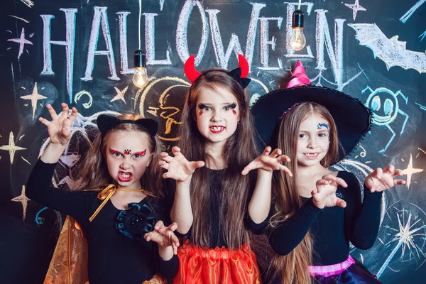 Meninas, vestidas com trajes de Halloween, mostram emoções de bruxas. Festa de Halloween com crianças de grupo . — Fotografia de Stock