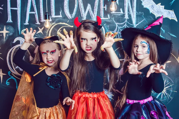 Las muchachas, vestidas con disfraces de Halloween, muestran emociones de brujas. Fiesta de Halloween con niños en grupo . — Foto de Stock