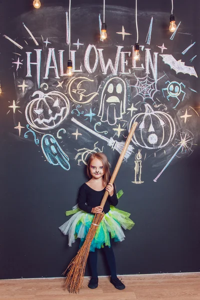 Menina vestida com trajes de Halloween. Posando no fundo da inscrição Halloween . — Fotografia de Stock