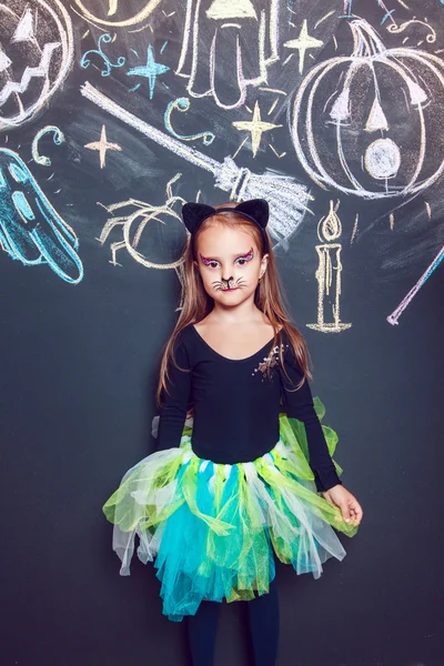 Menina vestida com trajes de Halloween. Posando no fundo da inscrição Halloween . — Fotografia de Stock