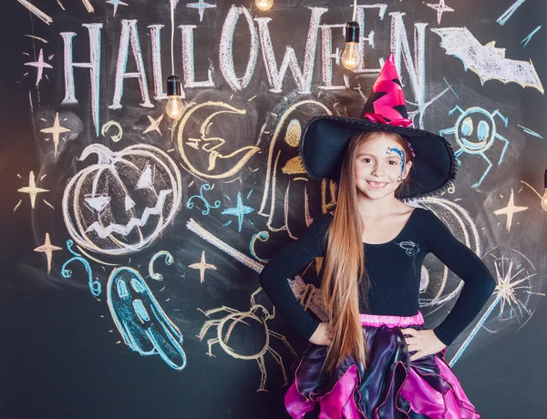 Ragazza vestita con costumi di Halloween. Posa sullo sfondo dell'iscrizione Halloween . — Foto Stock