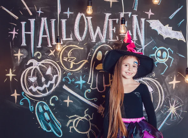 Menina vestida com trajes de Halloween. Posando no fundo da inscrição Halloween . — Fotografia de Stock