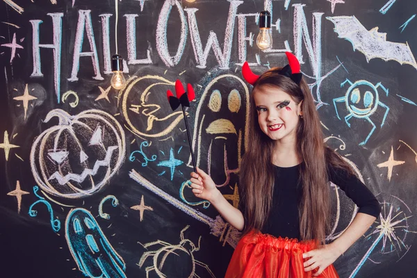 Chica vestida con disfraces de Halloween. Posando en el fondo de la inscripción Halloween . — Foto de Stock