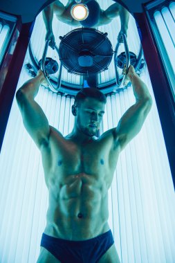 Yüzünde sakallı yakışıklı atletik adam bir tan sunroom içinde alır..