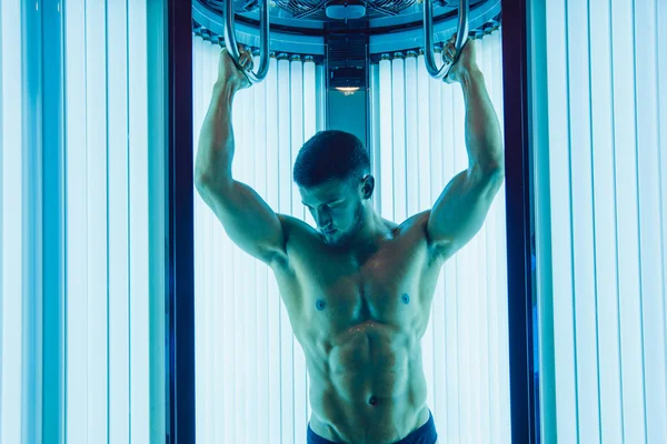 Yüzünde sakallı yakışıklı atletik adam bir tan sunroom içinde alır..