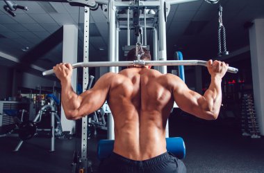 Çok güç atletik adam vücut geliştirmeci, egzersiz simülatörü ile yürütmek