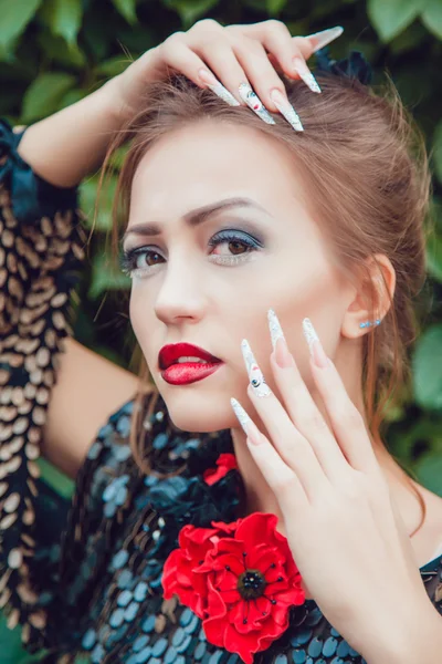 Schöne Mädchen mit einer Maniküre auf einem Hintergrund aus Blättern — Stockfoto