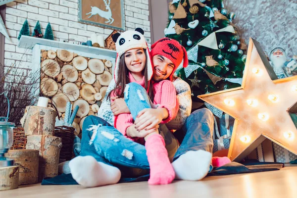 Um casal amoroso em chapéus engraçados posando em decorações de Natal — Fotografia de Stock