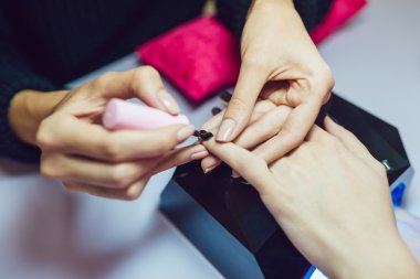 Manikür. Güzellik Salonu. Yakın çekim. Siyah oje uygulamak.