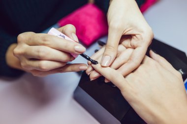 Manikür. Güzellik Salonu. Yakın çekim. Siyah oje uygulamak.