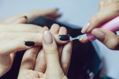 Manikür. Güzellik Salonu. Yakın çekim. Siyah oje uygulamak.