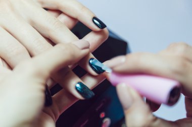 Manikür. Güzellik Salonu. Yakın çekim. Siyah oje uygulamak.