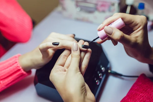 Manikür. Güzellik Salonu. Yakın çekim. Siyah oje uygulamak.