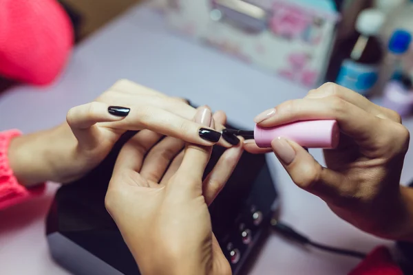 Manicure. Salon van de schoonheid. Close-up. Toepassing van de zwarte nagellak. — Stockfoto