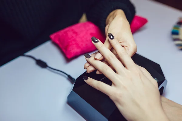 Manicure. Salon van de schoonheid. Close-up. Toepassing van de zwarte nagellak. — Stockfoto