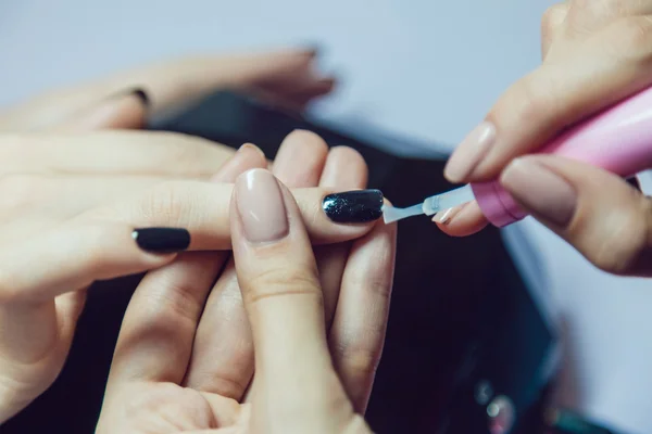 Manicure. Salão de beleza. Close-up. Aplicar esmalte preto . — Fotografia de Stock