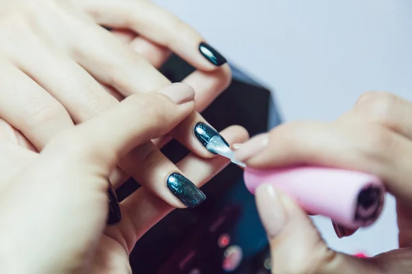 Manicure. Salon van de schoonheid. Close-up. Toepassing van de zwarte nagellak. — Stockfoto