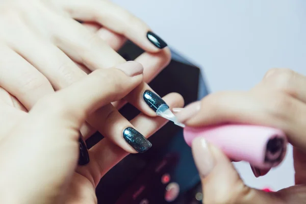 Manicure. Salão de beleza. Close-up. Aplicar esmalte preto . — Fotografia de Stock