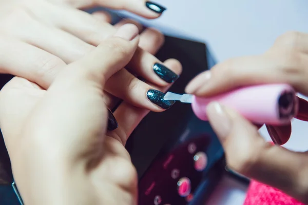 Manicure. Salão de beleza. Close-up. Aplicar esmalte preto . — Fotografia de Stock