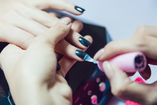 Manicure. Salon van de schoonheid. Close-up. Toepassing van de zwarte nagellak. — Stockfoto