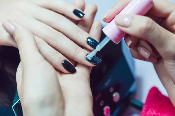 Manicure. Salon van de schoonheid. Close-up. Toepassing van de zwarte nagellak. — Stockfoto