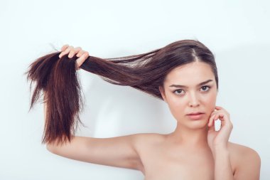 Güzel Asyalı kız saçını elinde tutar. Çıplak omuz.