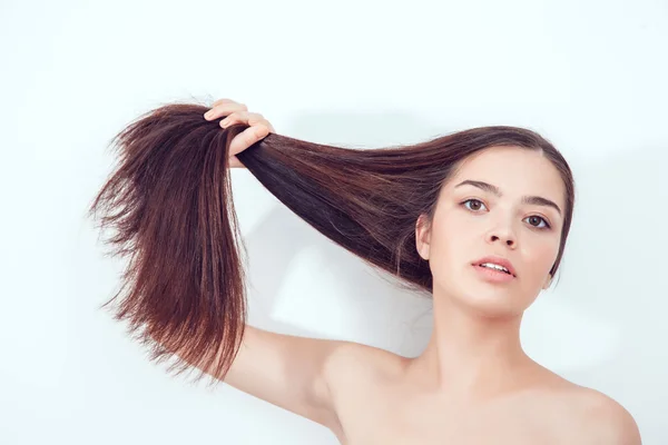 Schöne asiatische Mädchen hält ihr Haar in den Händen. Nackte Schultern. — Stockfoto