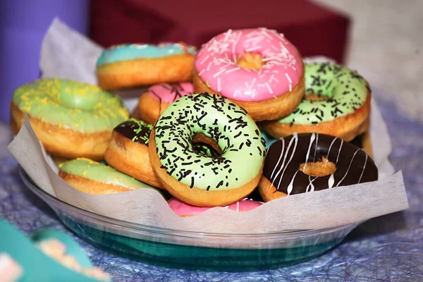 Donuts vidrados coloridos com polvilhas. Servido numa placa branca. doces doces tradicionais. doces bonitos e brilhantes, close-up — Fotografia de Stock