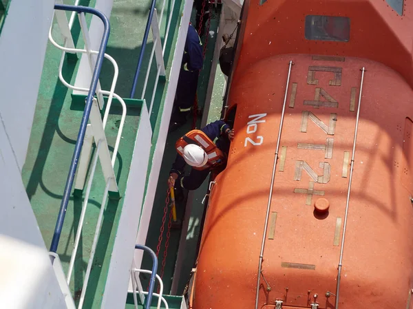 Gemideki açık denizde terk edilmiş gemi sondajları. Gemiden ayrılıp turuncu filikaya binen kişi. Yatay çerçeve.