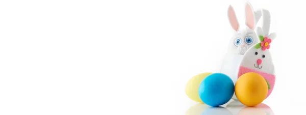 El yapımı beyaz tavşan sepeti ve beyaz arka planda üç renkli yumurta..