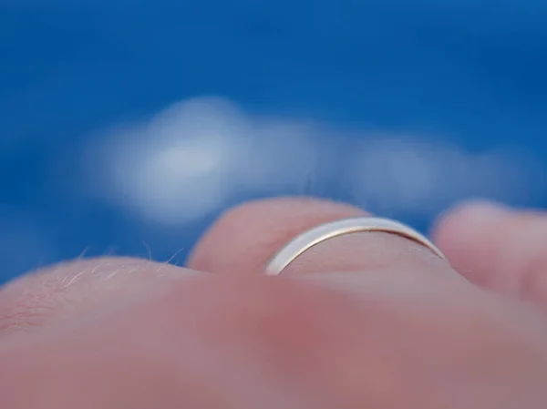 Parmağındaki alyansa yakından bak. Mavi gökyüzüne karşı tek bulutlu..