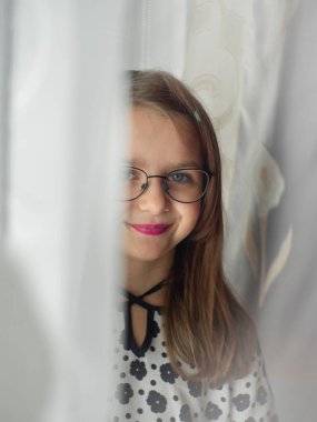 Gözlüklü ve pembe dudaklı genç kız gün boyunca pencerenin yanında duruyor..