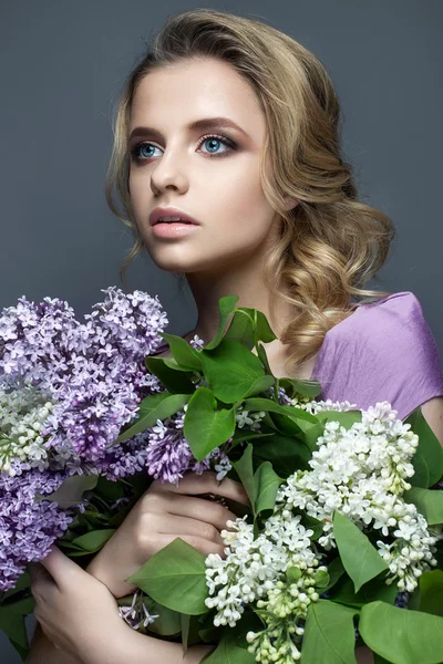 Güzel kız mor elbise ve leylak bir buket. Bahar görüntüde modelidir.
