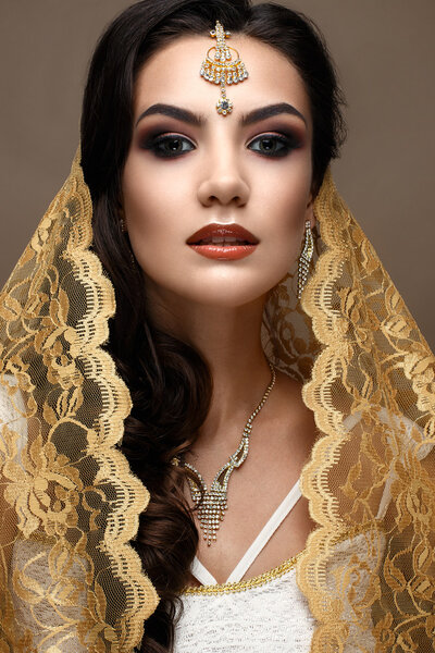 Красивая девушка в индийском стиле с шарфом на голове. Модель с креативным и ярким макияжем
. 