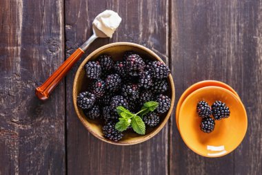 Ahşap rustik zemin üzerine bir kase içinde olgunlaşmış taze böğürtlen