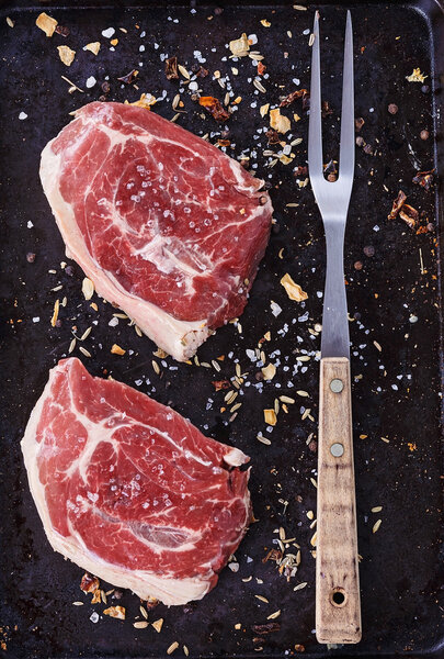 Red meat and fork over rustic metal background