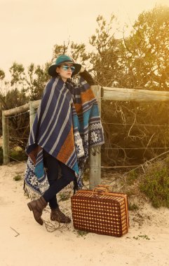 Young hipster girl in poncho with vintage suitcase clipart