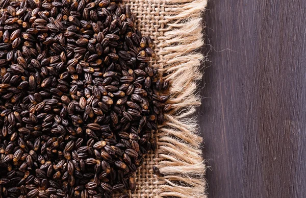 Черный ячмень зерна на деревенском деревянном фоне — стоковое фото
