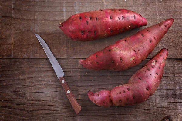 Rustik ahşap arka plan üzerinde kırmızı tatlı patates — Stok fotoğraf