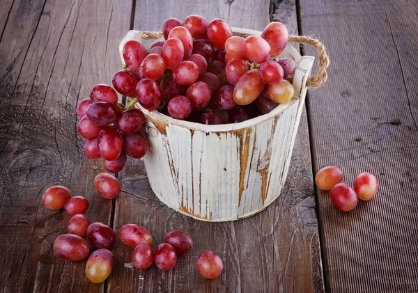 Красный виноград в винтажном деревянном ведре на деревянном фоне — стоковое фото