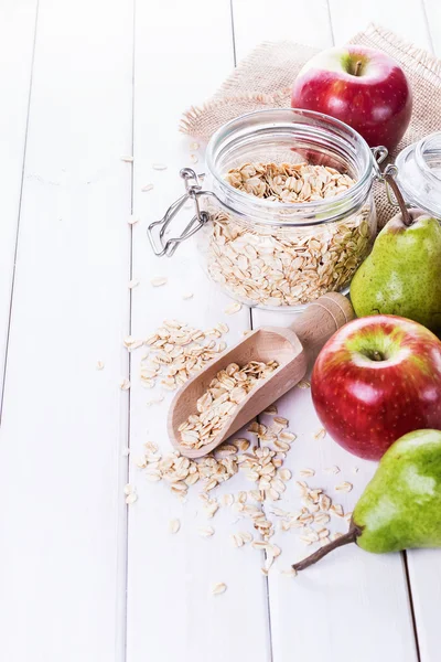 Fresh fruits and rolled oats over white background — Stock Photo, Image